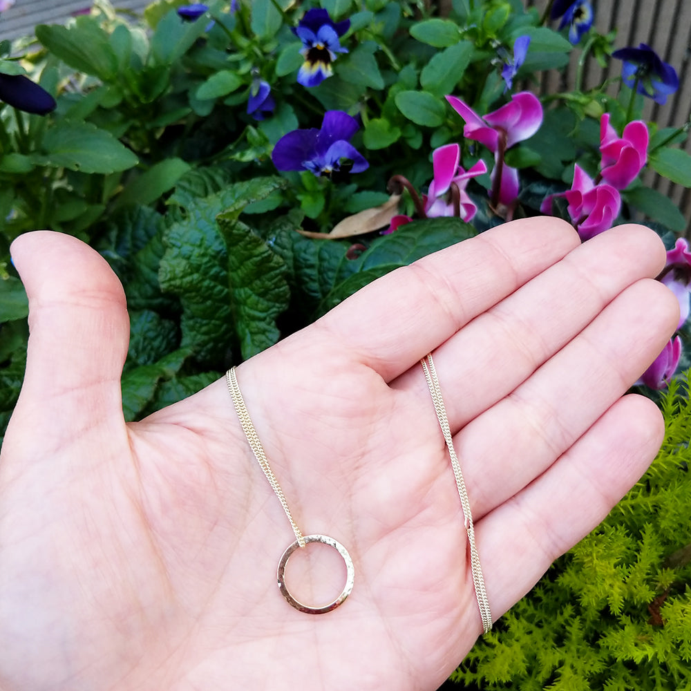 dainty gold circle necklace in hand