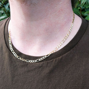 gold figaro chain on man's neck