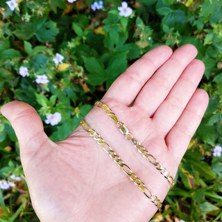 women's gold figaro chain in hand for scale