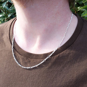 silver figaro chain on man's neck