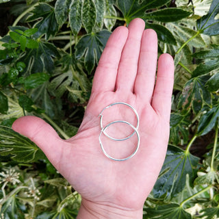 silver hoop earrings in hand for scale