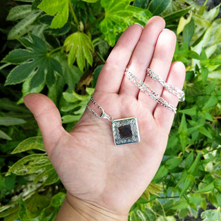 women's silver locket in hand for scale