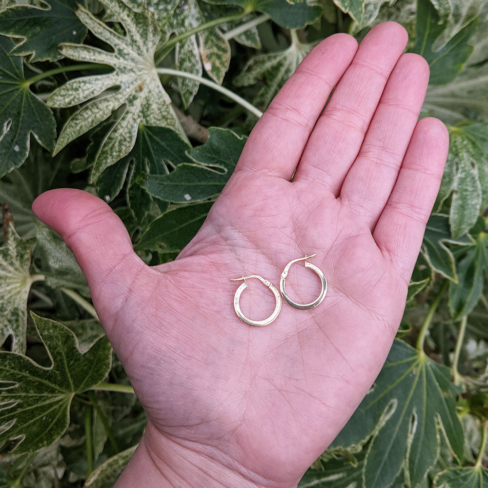 small yellow gold hoops in hand for scale