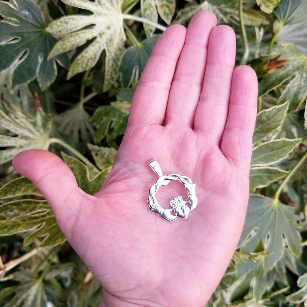 silver claddagh pendant in hand for scale