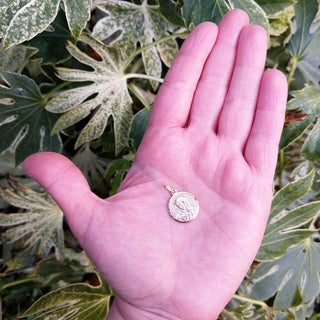 virgin mary pendant in hand for scale