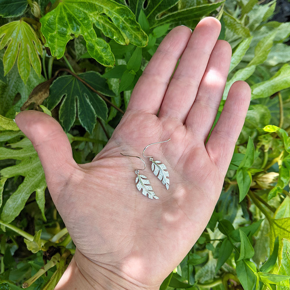 leaf earrings in hand for scale