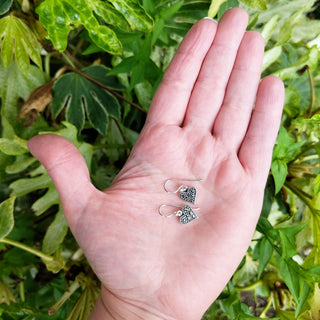 heart dangle earrings in hand for scale