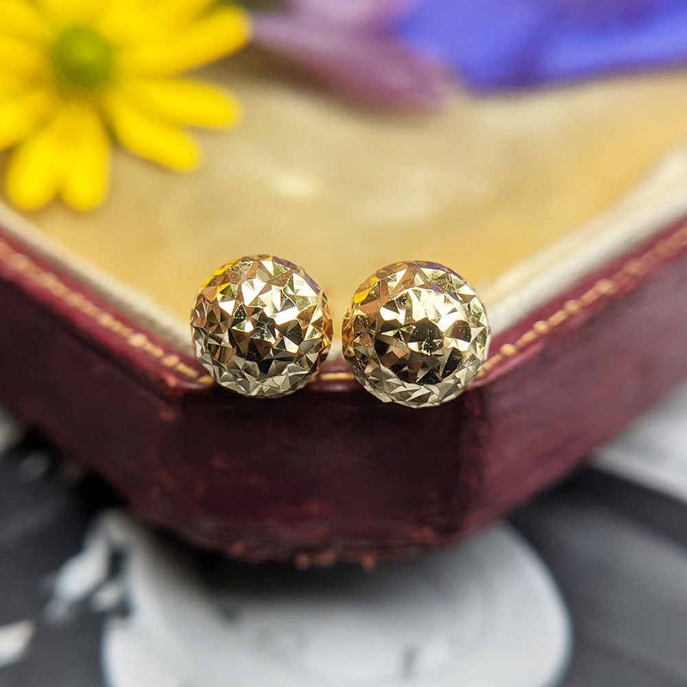 close up of disco ball earrings in yellow gold