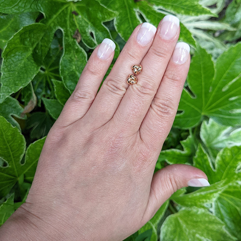rose gold knot studs in hand for scale