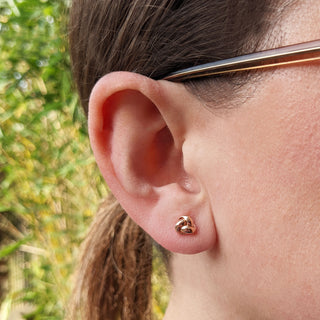 rose gold trinity knot studs in ear