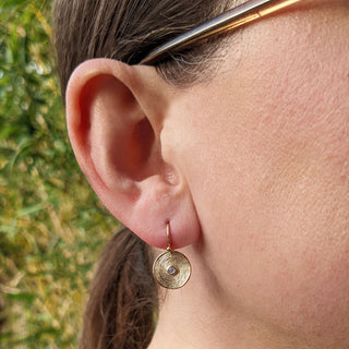 gold disc earrings in ear