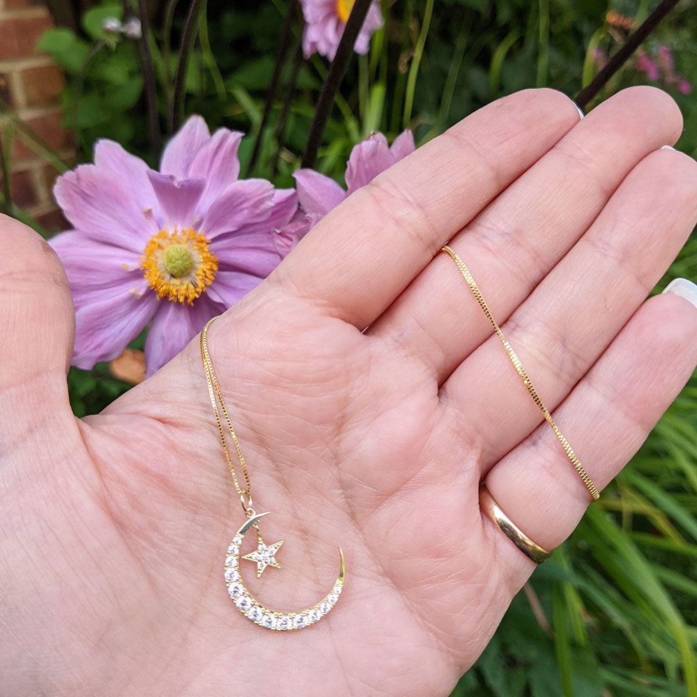 moon and star pendant necklace in hand for scale