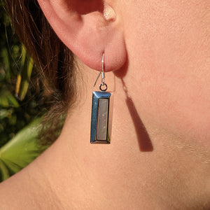 silver rectangular earrings in ear