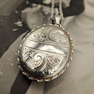 large oval silver locket with Victorian engraved design